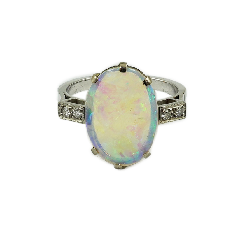 A white gold? and single stone oval cabochon opal set ring, with four stone diamond set shoulders